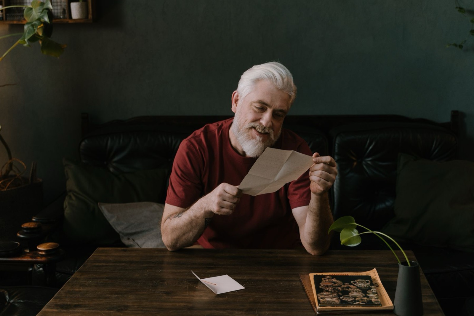 A man reading a letter at a table in a dark room